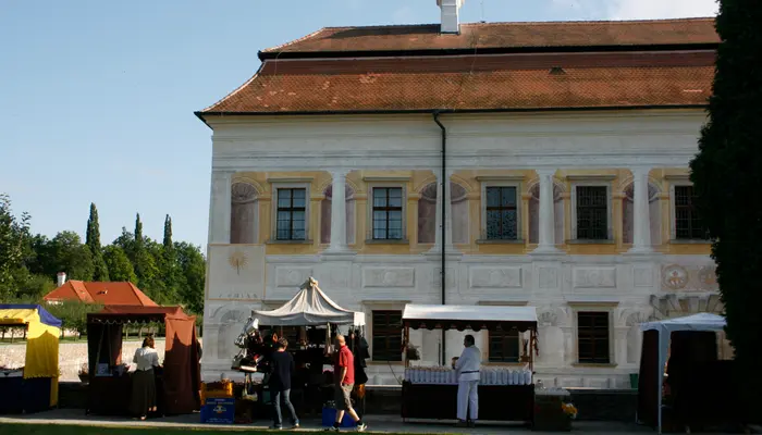 Historická budova s tržními stánky před zámkem Kratochvíle v Netolicích.