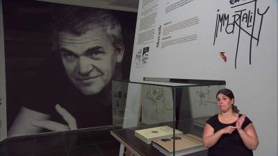 Výstava o Milane Kundere s jeho portrétem a knihou.