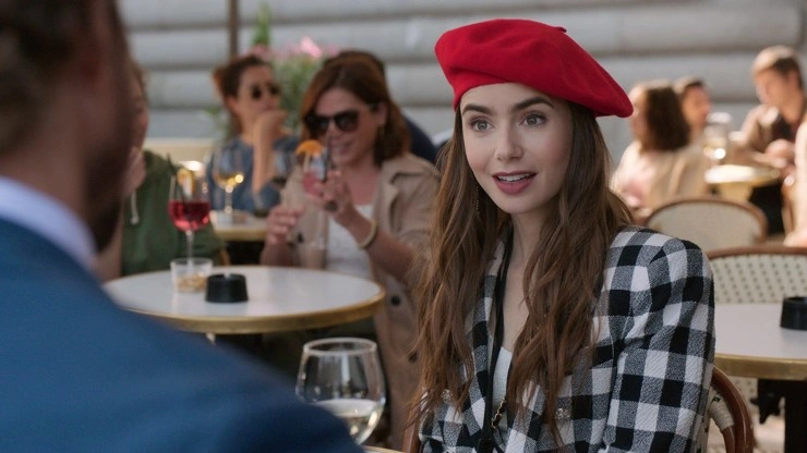 Herečka Lily Collins v červeném klobouku na venkovní kavárně.