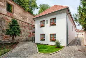 Bílá historická budova s červenou střechou v Nymburku.