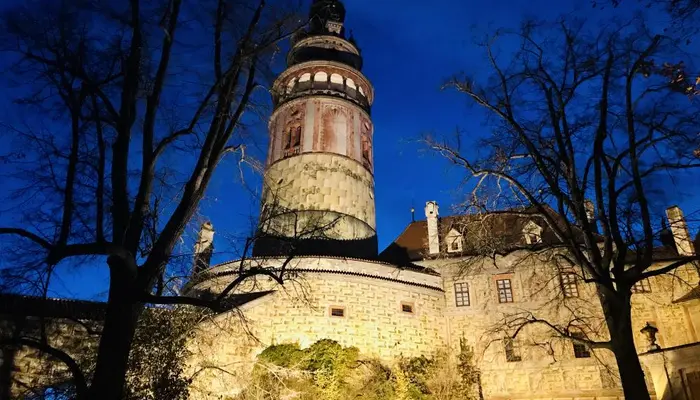 Zámek Český Krumlov s věží osvětlenou v noci.