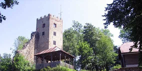 Starověká kamenná věž v Domažlicích s dřevěnou altánovou konstrukcí.