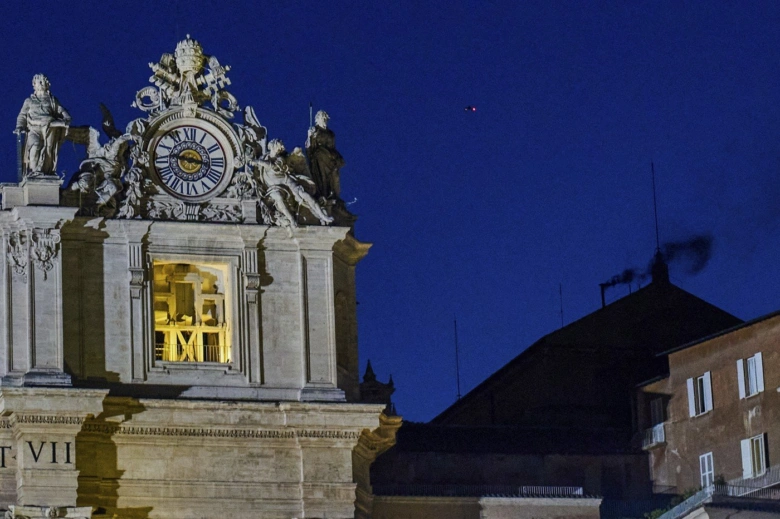 Iluminovaná věž s hodinami na pozadí noční oblohy.