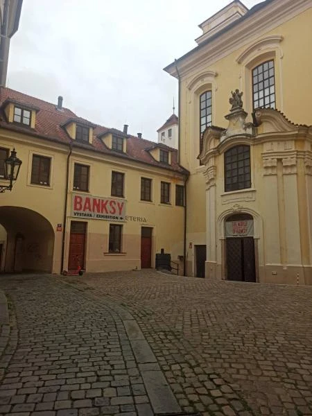 Fotografie Banksyho umění v pražském dvore s červeným nápisem.