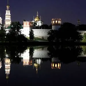 Noční pohled na osvětlený Kreml v Moskvě s odrazem ve vodě.