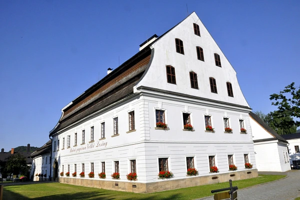 Historická bílá dřevěná budova v centru Velkých Losin.