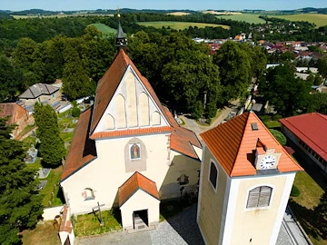 Historický kostel v obci u Benešova s červenou střechou.