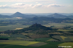 Pohled na kopci s hradními zbytky a okolní poli.