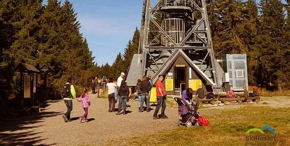 Turisté u nohy věže v lesu.