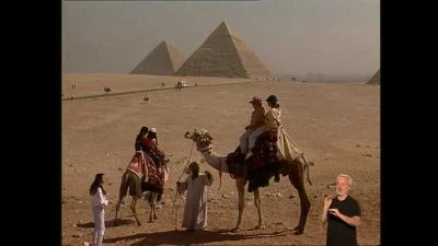 Turisté na kamelech u pyramid v poušti s Gízou.