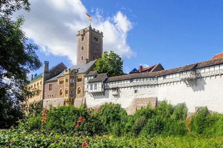 Historický hrad v Německu s věží a zelenou vegetací.