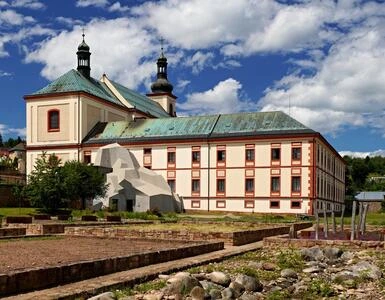 Historická budova s věžemi nad archeologickými zbytky ve Vrchlabí.