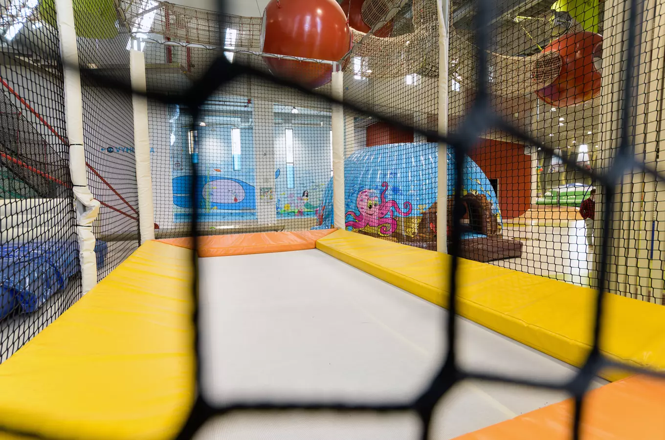 Vnitřní hřiště s trampolíny a barevnými dekoracemi pro děti.