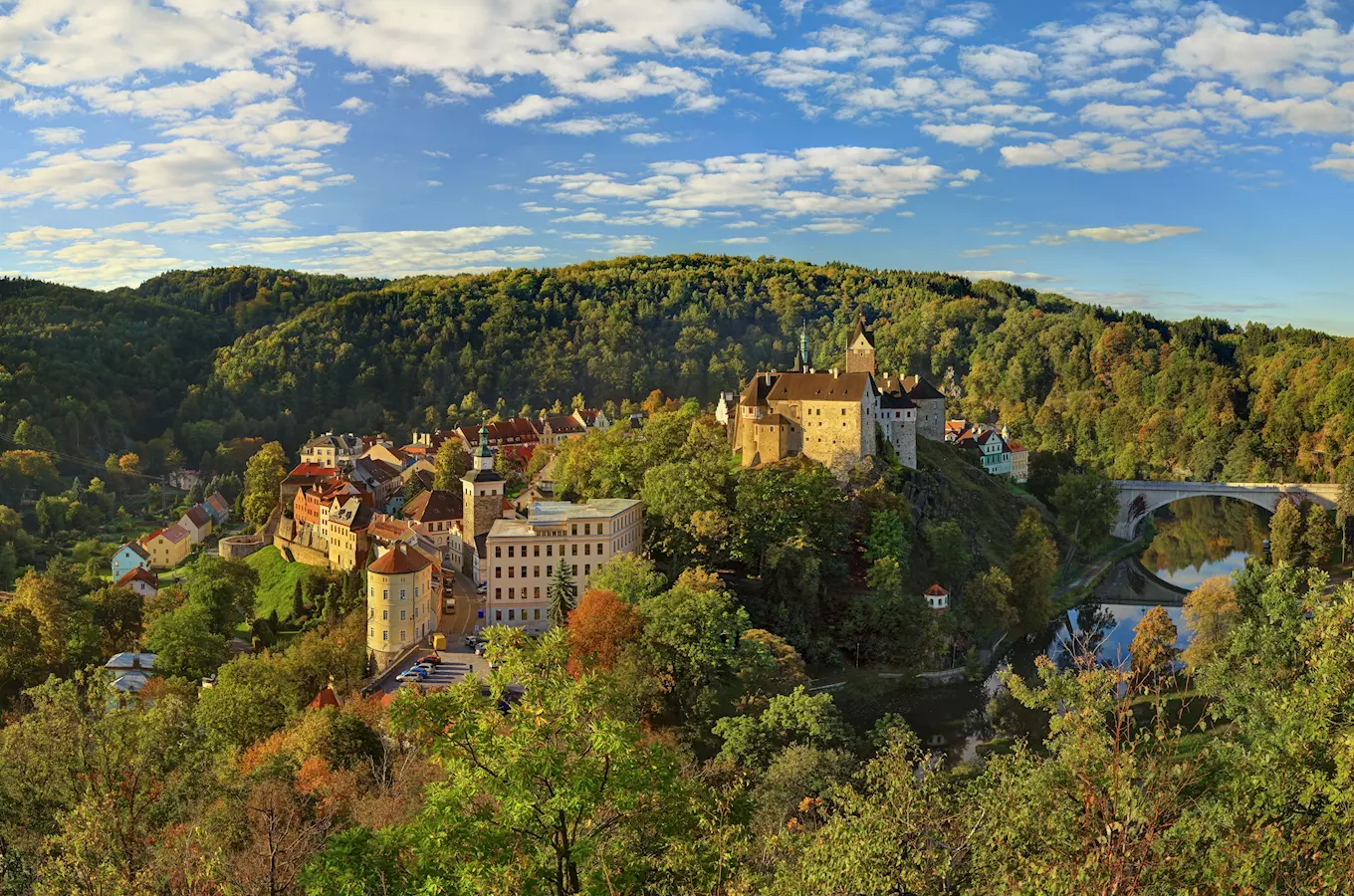 Pohled na hrad Loket s vesnicí podél řeky v přírodě.