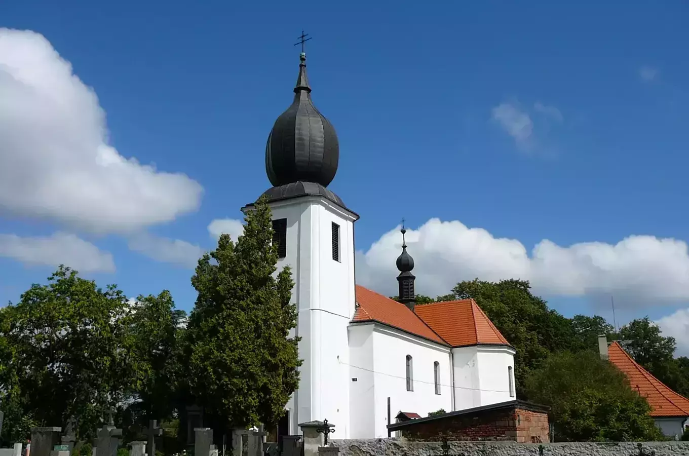 Bílá kostel s cibulovou kupolí na modré obloze