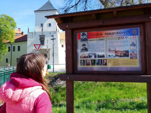 Dívka čte informační tabuli o procházce Masarykových v Kroměříži.