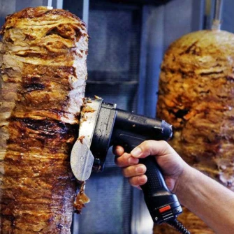 Ruční stříhání kebabu z vertikálního grilu na plátek.