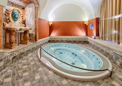 Luxusní vnitřní wellness s horkou vanou a dekorativními prvky.