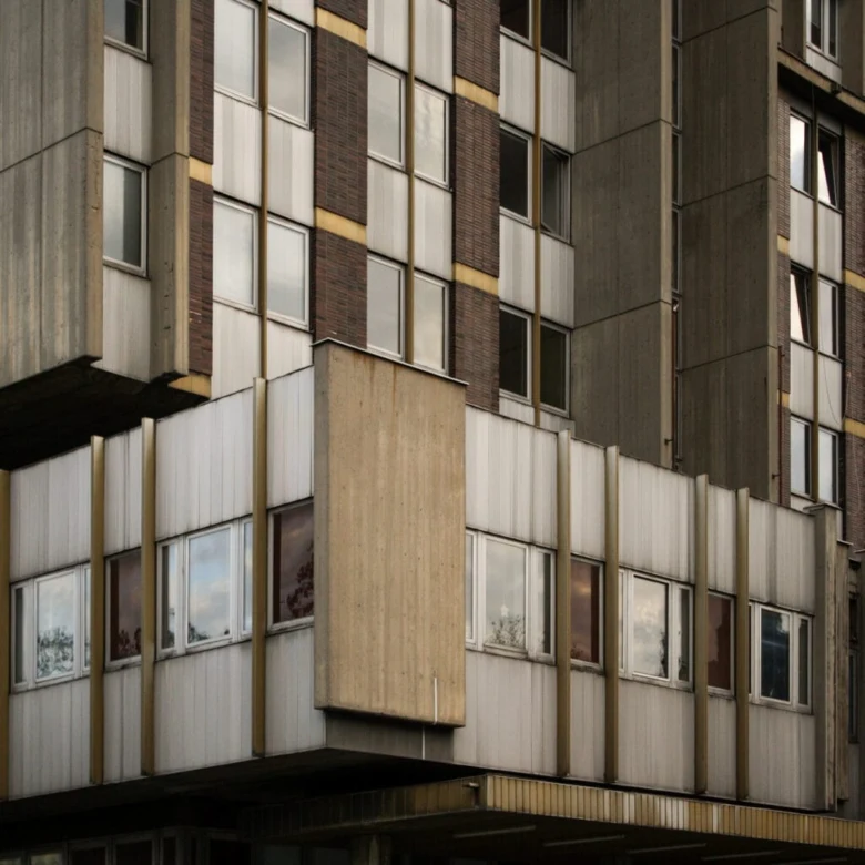 Brutalistní fasáda panelového domu s betonovými prvky.