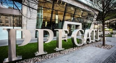 Moderní budova s výrazným nápisem PPE GATE před skleněnou fasádou.