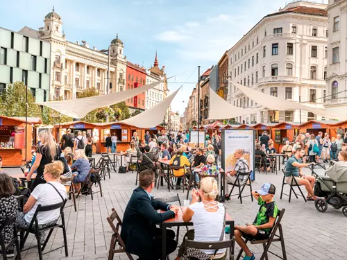 Venkovní trh s občerstvením na brněnském náměstí za slunečného dne.