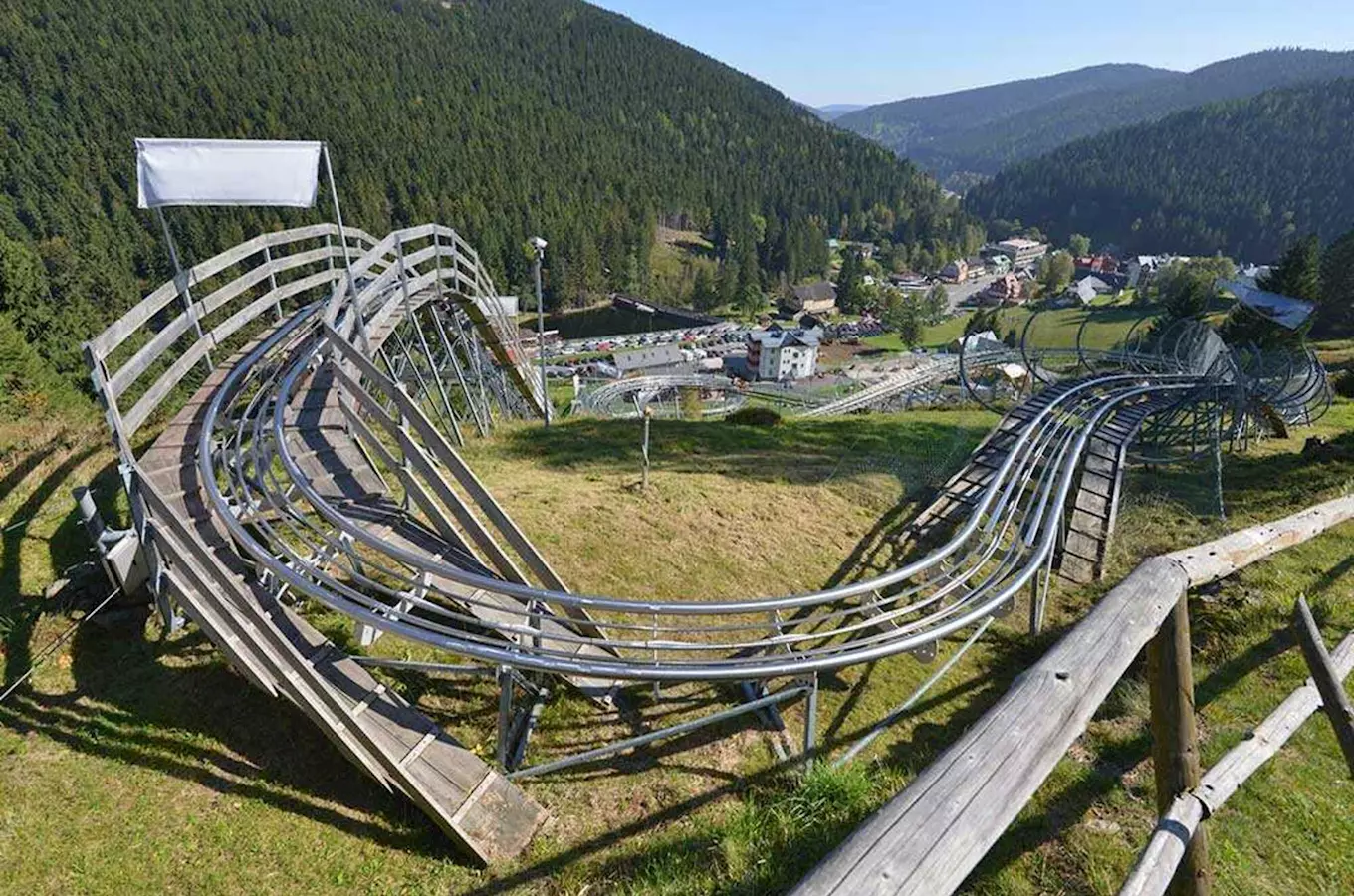 Dřevěná bobová dráha v českých horách s lesním pozadím.