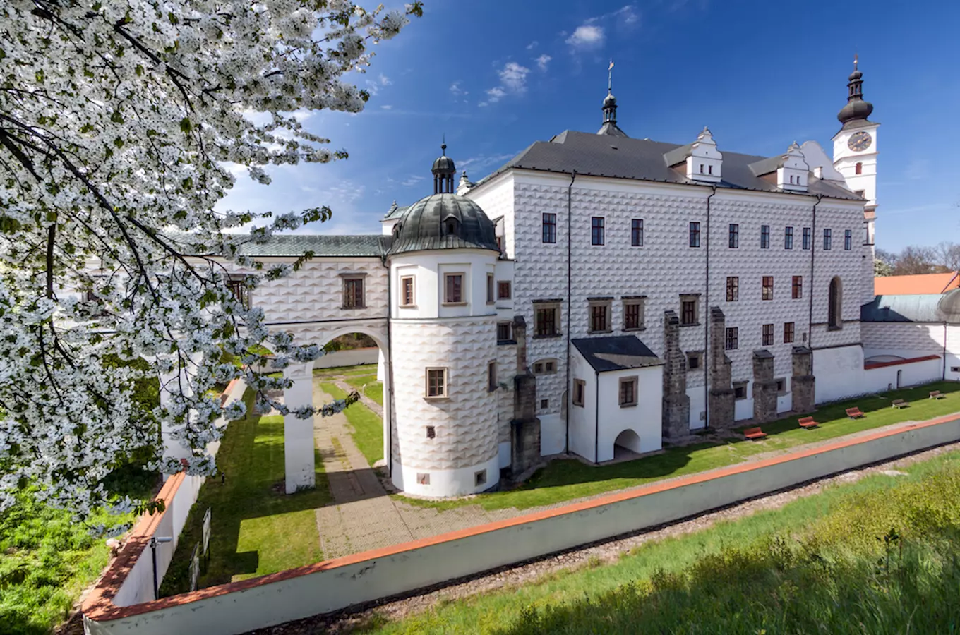Historická bílá budova s věží v Pardubicích pod modrou oblohou.