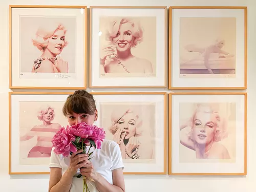 Žena s růžemi před výstavou portrétů Marilyn Monroe v Praze.