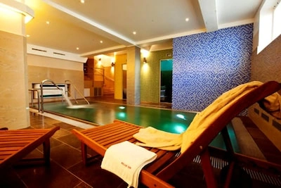 Vnitřní bazén v hotelu s lehátky pro relaxaci.