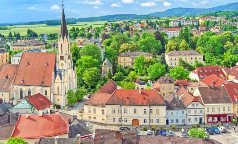 Pohled na historické město v Rakousku s kostelem a střechami.