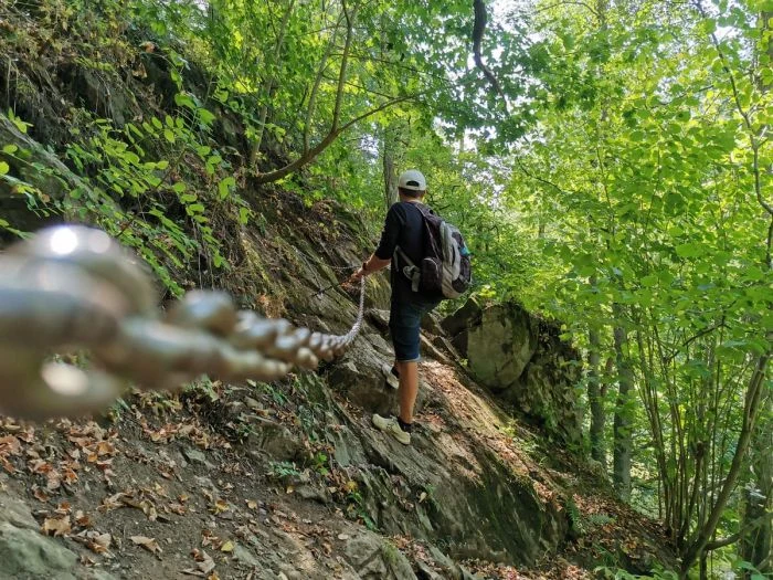 Turista stoupá po skále s lanem v lese na Devět skalách