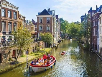 Lodička plná turistů pluje kanálem v Amsterodamu.