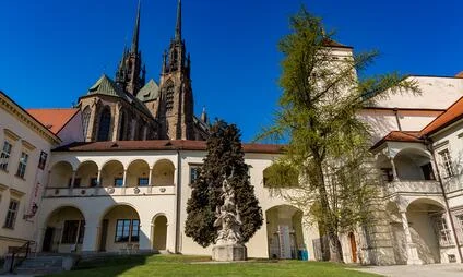 Kostel svatého Petra v Brně s klášterním dvorem pod modrou oblohou.