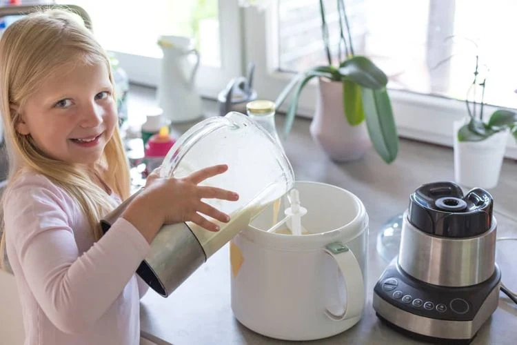 Dívka nalévá mléko do domácího zmrzlinovače.