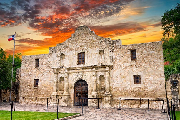 Historická budova Alamo v Texasu s texaskou vlajkou.
