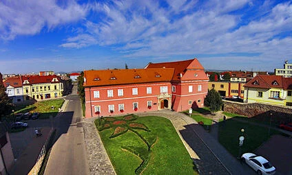 Pohled na Uherské Hradiště s červenými střechami, zelenou trávou a modrou oblohou.