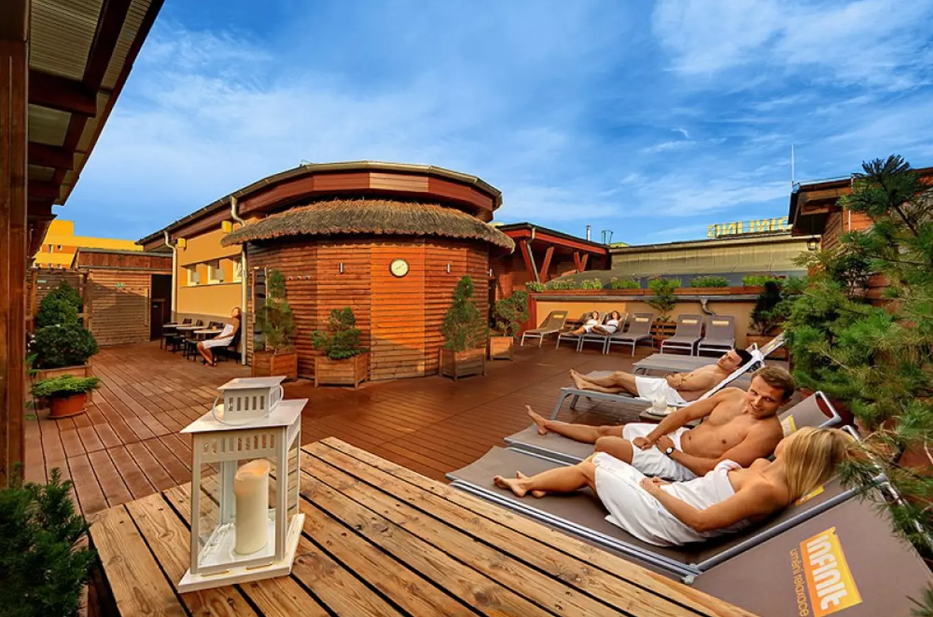 Dřevěná terasa wellness centra s saunou a lehátky pro relaxaci.