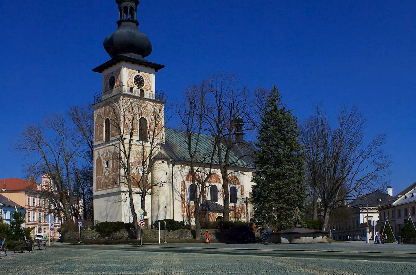 Historický kostel s věží uprostřed náměstí v Novém Městě na Moravě.