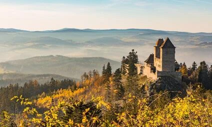 Zámek na kopci s lesy a mlhou nad Kašperskou horou