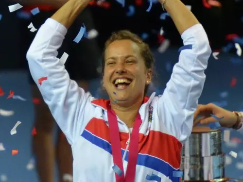 Petra Kvitová vítězně zvedá ruce s medailí.