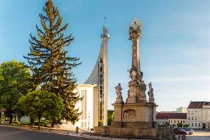 Historická sloupová socha na náměstí v Hustopečích pod modrou oblohou.