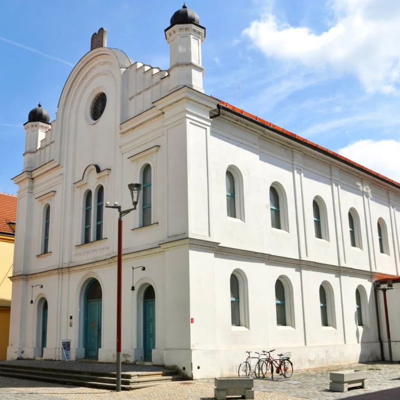 Bílá synagoga v Břeclavi s obloukovými okny na modrém nebi.