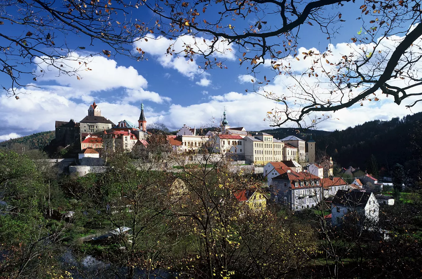 Pohled na hrad Loket s okolními domy pod modrou oblohou.