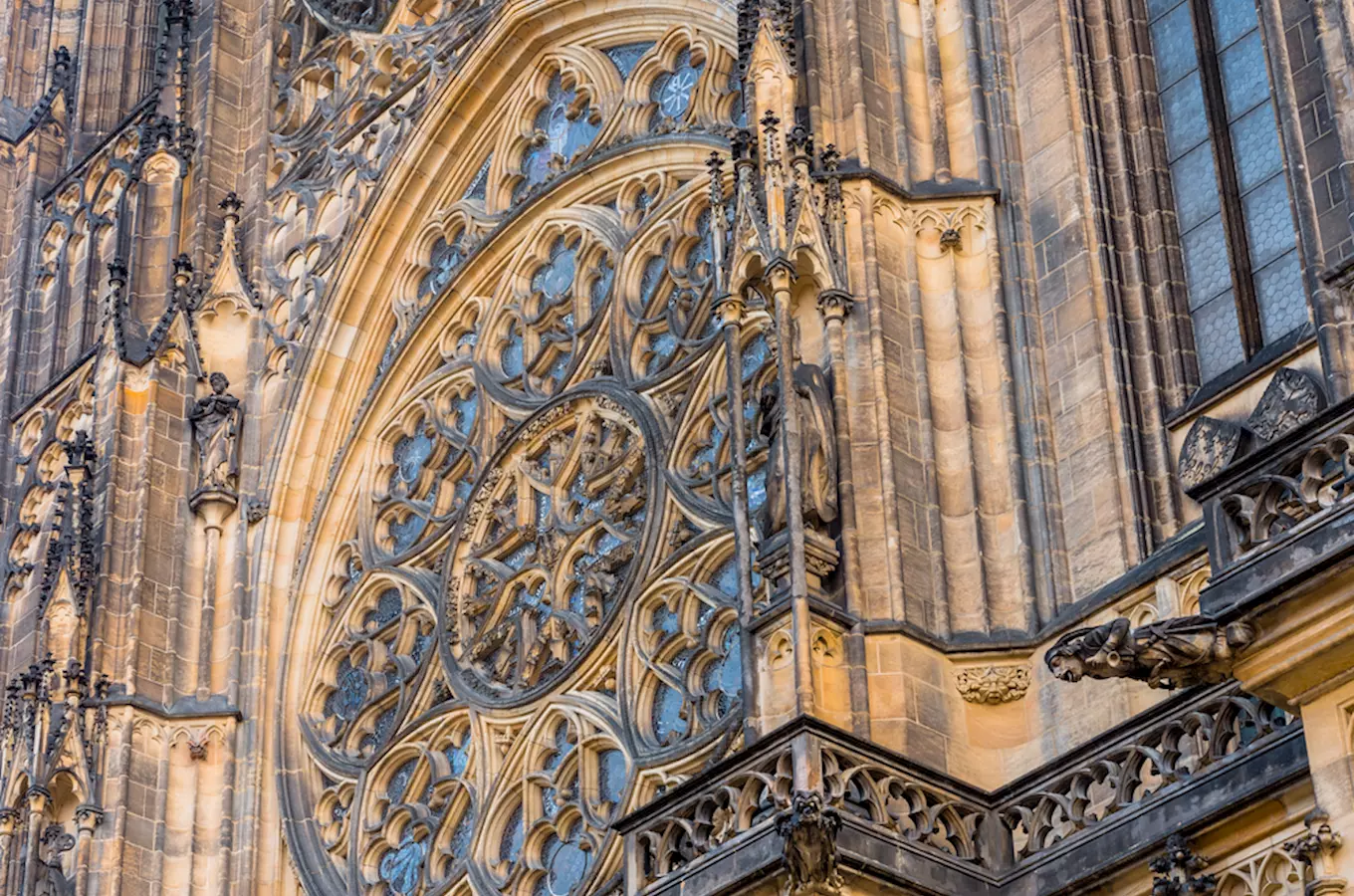 Detail fasády katedrály svatého Víta s oknem a sochami.