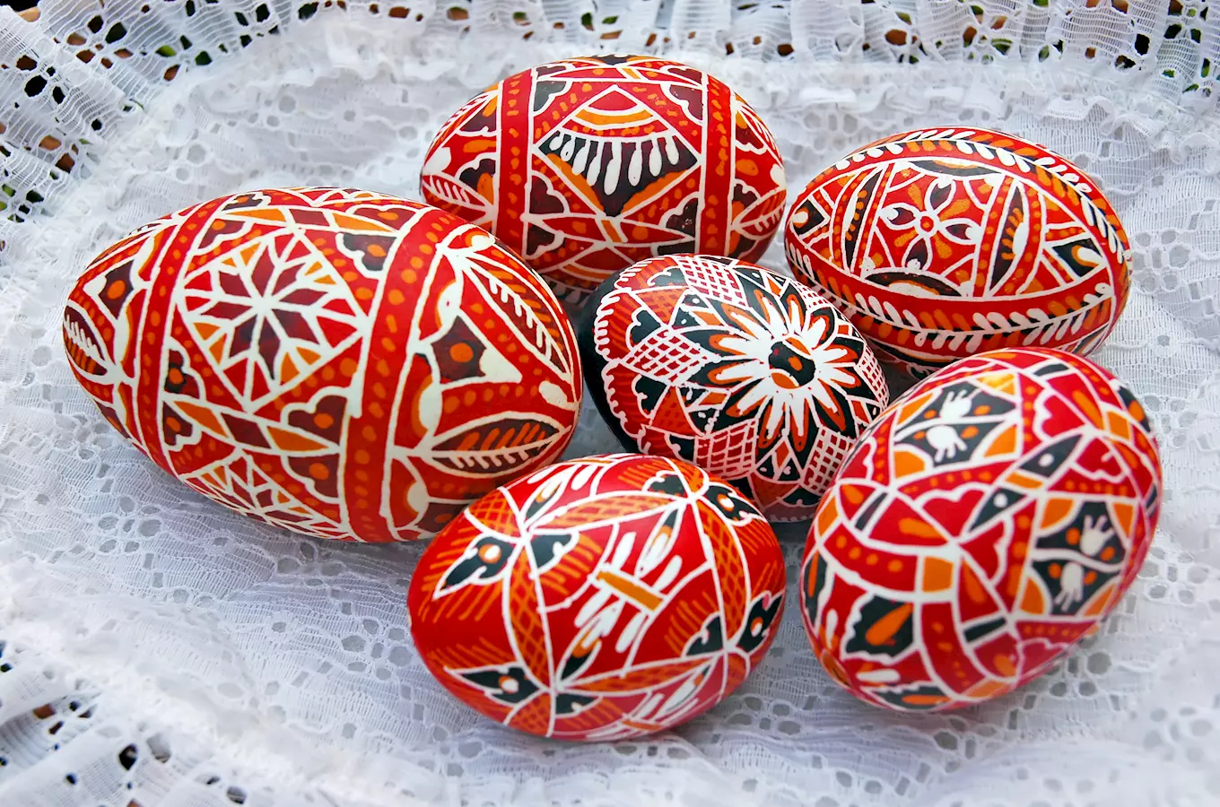 Vyrobené vajíčka s tradičními vzory na bílém krajkovém podkladu.