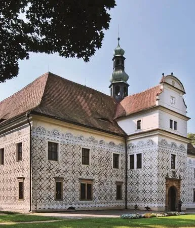 Historická budova s věží v Lanškrouně na pozadí zelené trávy.