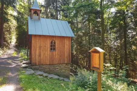 Malý dřevěný kostelík v lese na okraji Krkonoš.
