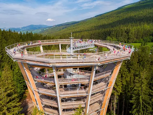 Velká dřevěná rozhledna v Krkonoších s turisty na terase.