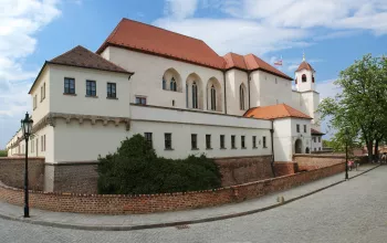 Zámek v Moravském Krumlově s červenou střechou a věží pod modrou oblohou.