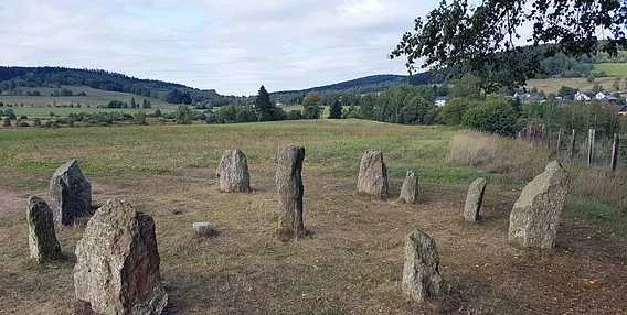 Kamenný kruh v přírodě s kopci na pozadí